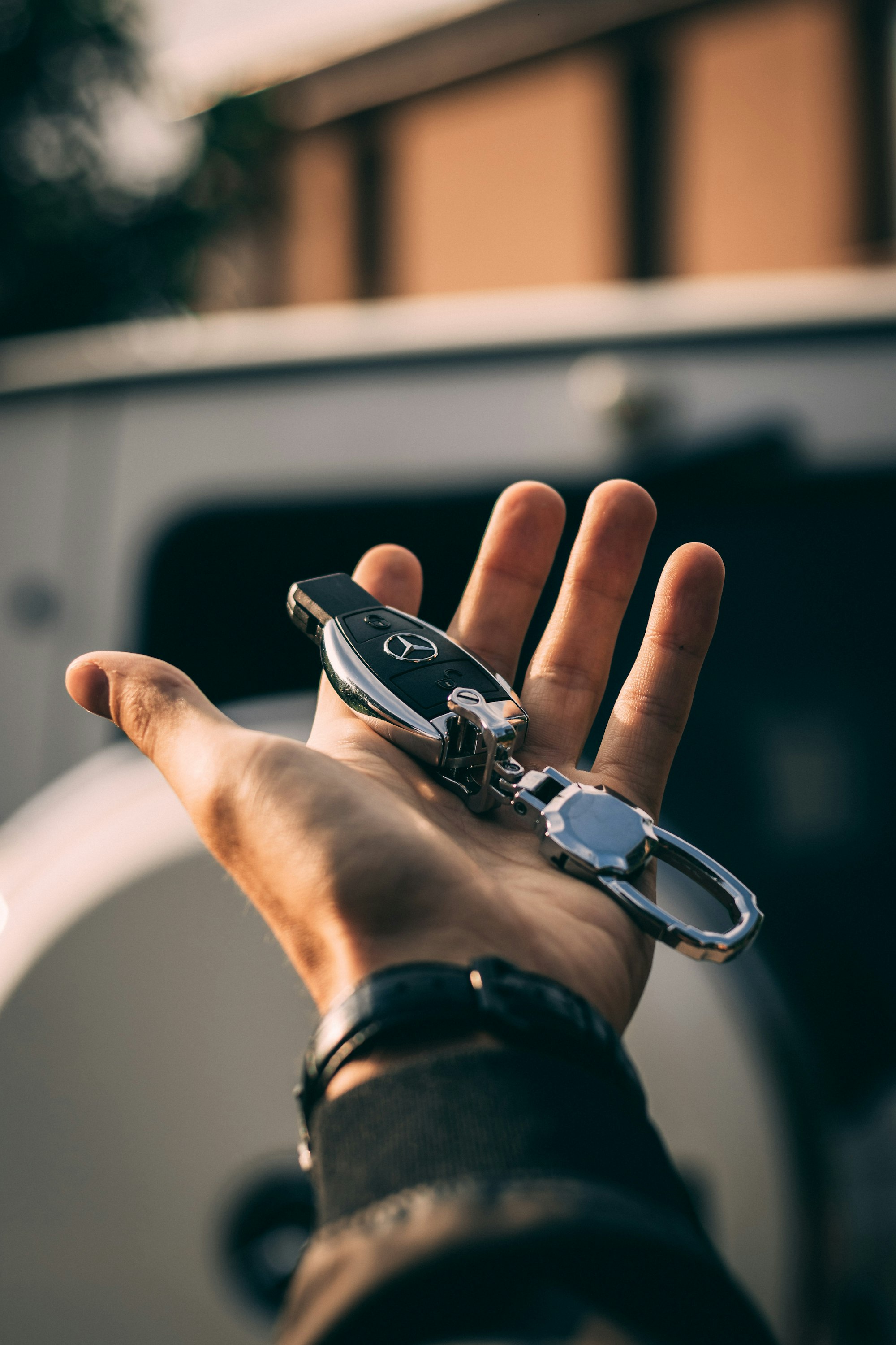Mercedes key fob in hand beside car